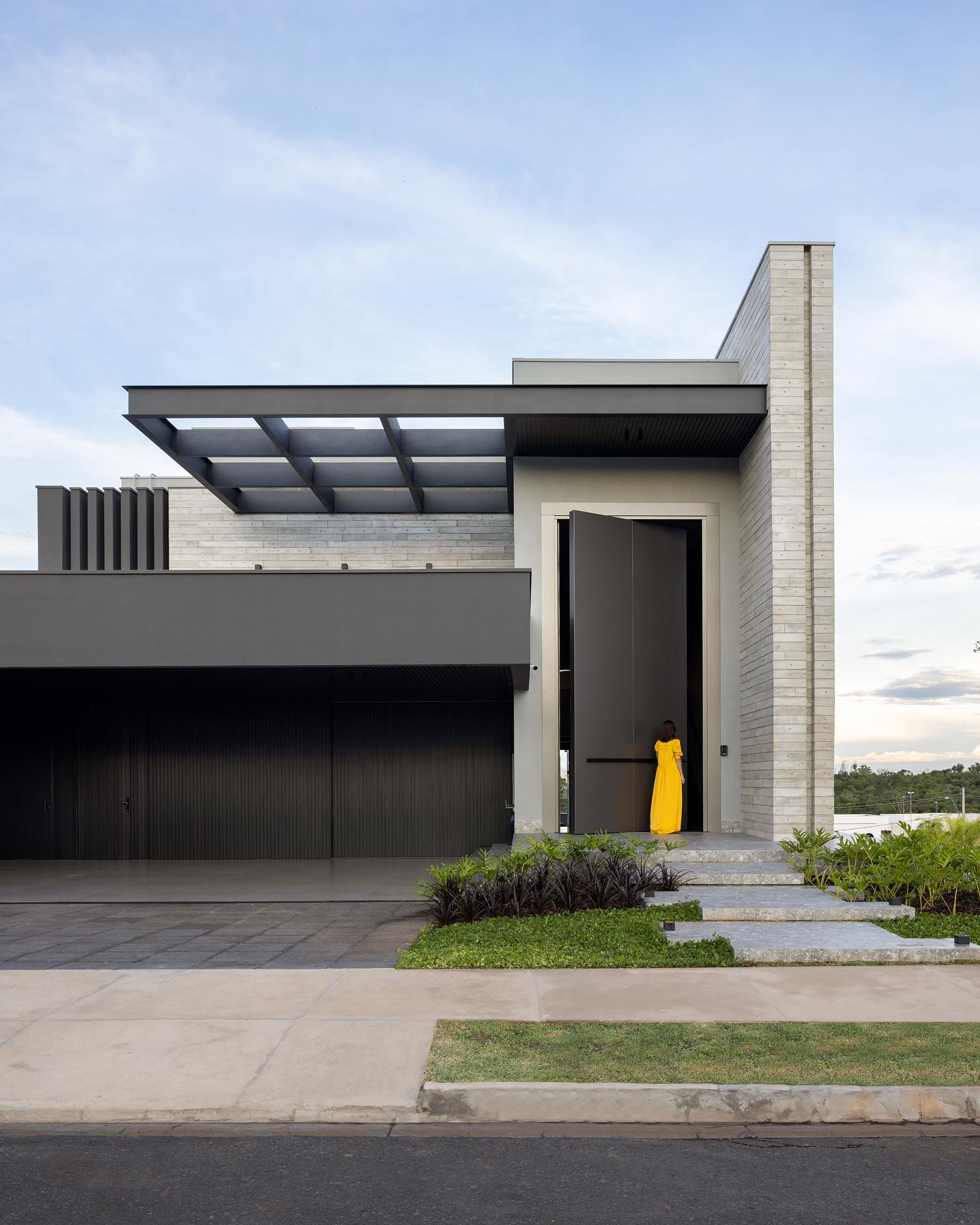 Fachada de casa de esquina preta e cinza com concreto e alumínio